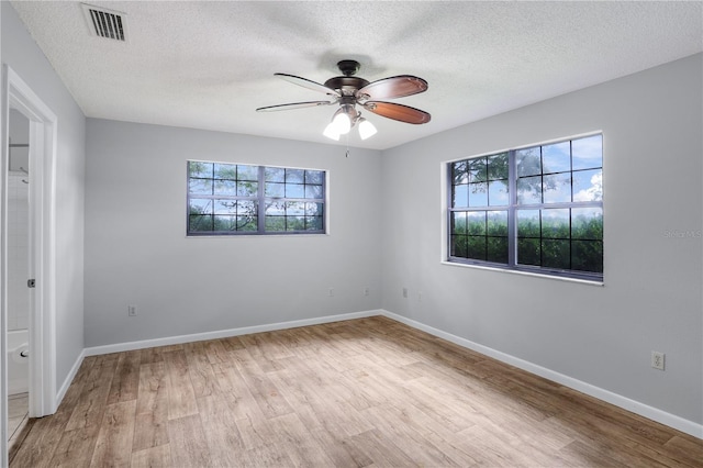 spare room with a ceiling fan, wood finished floors, visible vents, and baseboards