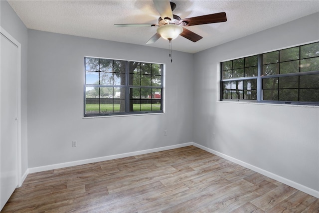 unfurnished room featuring a textured ceiling, baseboards, and wood finished floors