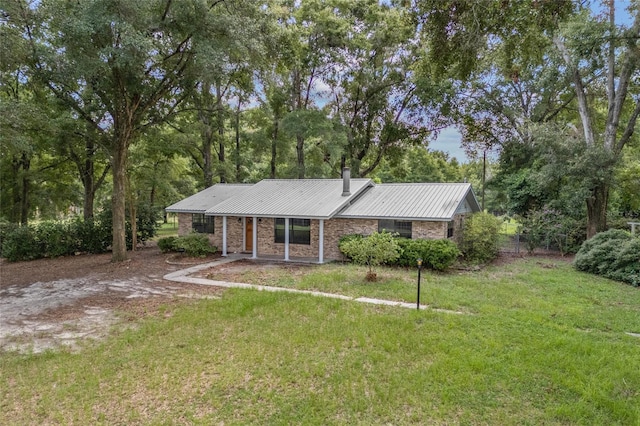 view of front of home featuring a chimney, metal roof, and a front yard