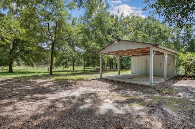 view of yard featuring driveway, a carport, and an outbuilding