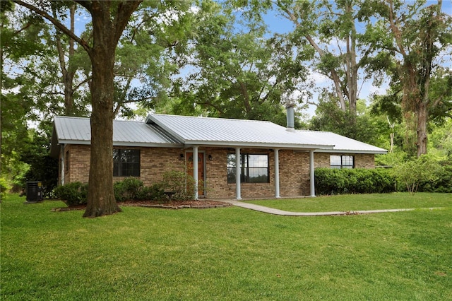 ranch-style house with metal roof, brick siding, and a front yard