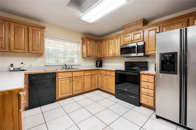 kitchen featuring black appliances, sink, and light tile patterned floors