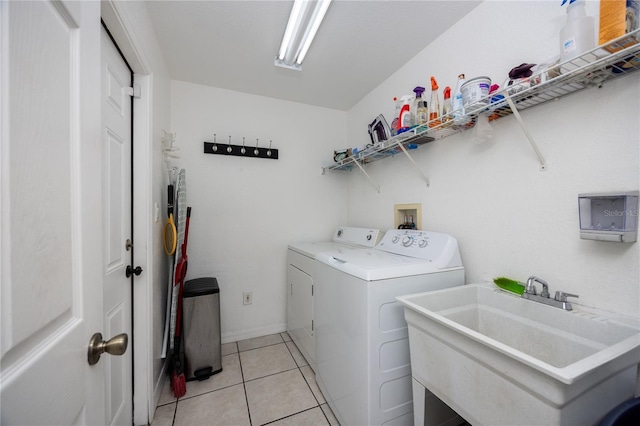 clothes washing area featuring washing machine and clothes dryer, light tile patterned floors, and sink