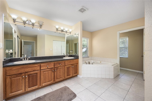 bathroom featuring tiled tub, vanity, and tile patterned floors