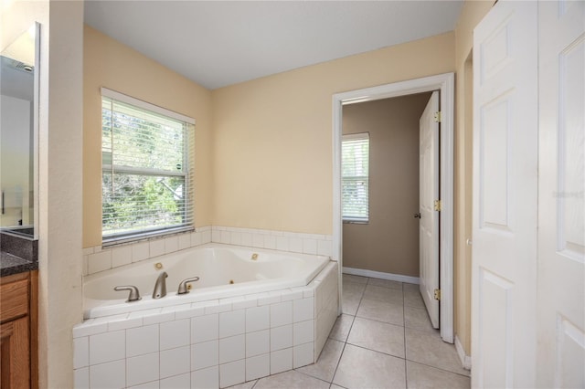 bathroom with a relaxing tiled tub, vanity, and tile patterned flooring