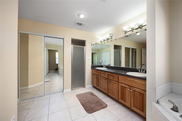 bathroom with a textured ceiling, independent shower and bath, tile patterned flooring, and vanity