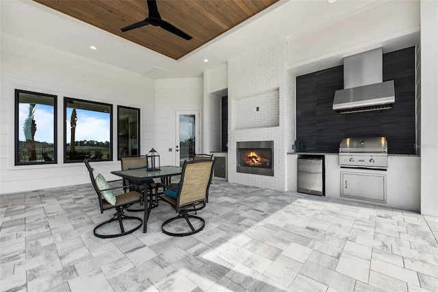 view of patio featuring grilling area, a large fireplace, exterior kitchen, and ceiling fan