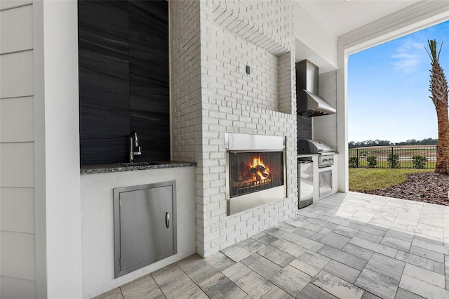 view of terrace with sink, an outdoor brick fireplace, and grilling area