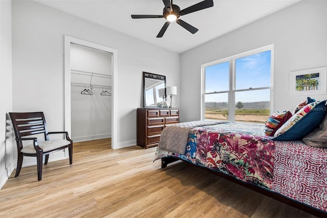 bedroom with ceiling fan, a closet, light wood-type flooring, and a spacious closet