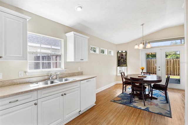 kitchen with light wood-type flooring, vaulted ceiling, white dishwasher, and white cabinetry