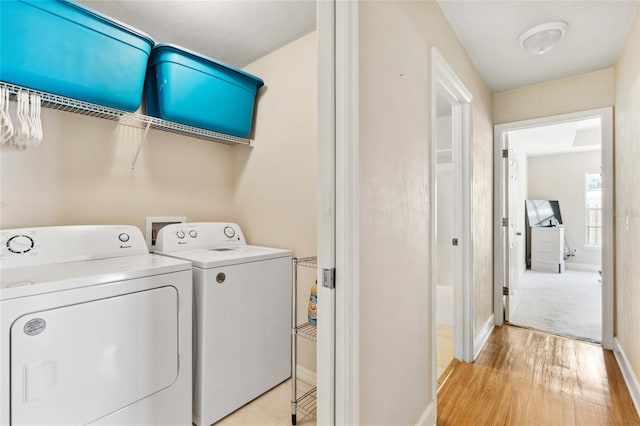 laundry area with independent washer and dryer and light hardwood / wood-style flooring