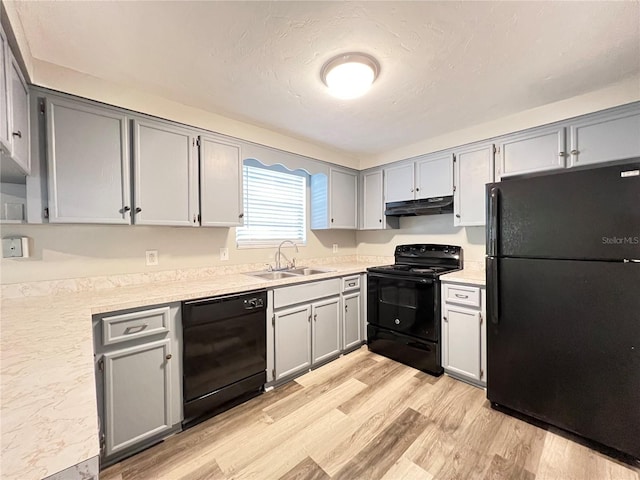 kitchen with gray cabinetry, black appliances, sink, and light wood-type flooring