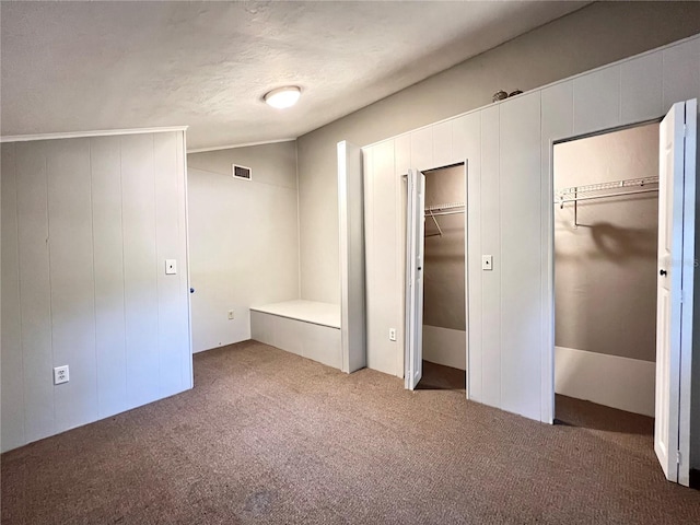 unfurnished bedroom featuring multiple closets, lofted ceiling, and carpet flooring