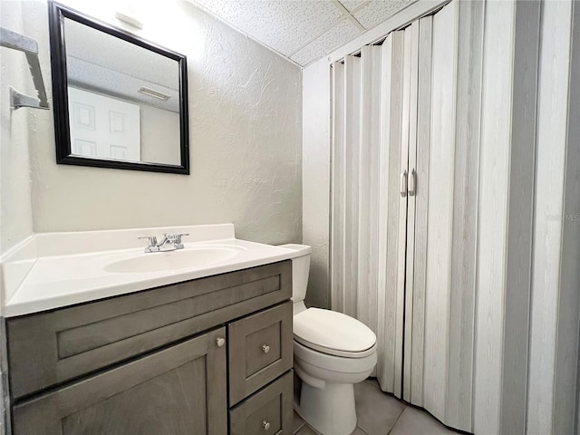 bathroom with tile floors, toilet, and large vanity