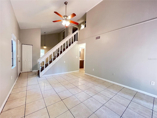 unfurnished living room with a towering ceiling, ceiling fan, and light tile flooring