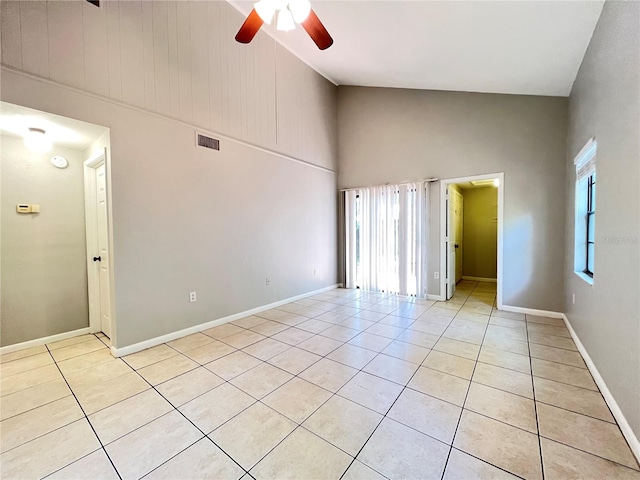 empty room with high vaulted ceiling, ceiling fan, and light tile flooring