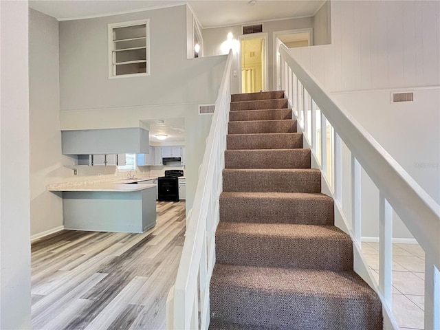 stairway featuring built in shelves, sink, and light wood-type flooring