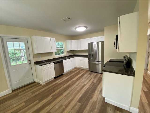 kitchen with white cabinetry, dark hardwood / wood-style floors, appliances with stainless steel finishes, and sink