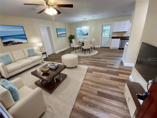 living room featuring ceiling fan with notable chandelier and hardwood / wood-style floors