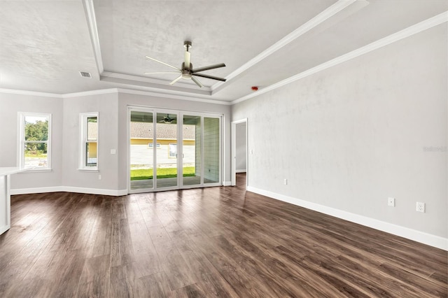 unfurnished living room featuring a tray ceiling, dark hardwood / wood-style floors, crown molding, and ceiling fan