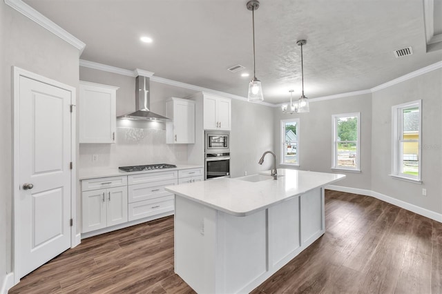 kitchen featuring dark hardwood / wood-style floors, hanging light fixtures, wall chimney exhaust hood, appliances with stainless steel finishes, and sink