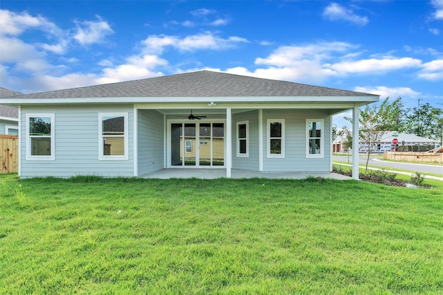 rear view of property featuring ceiling fan and a yard