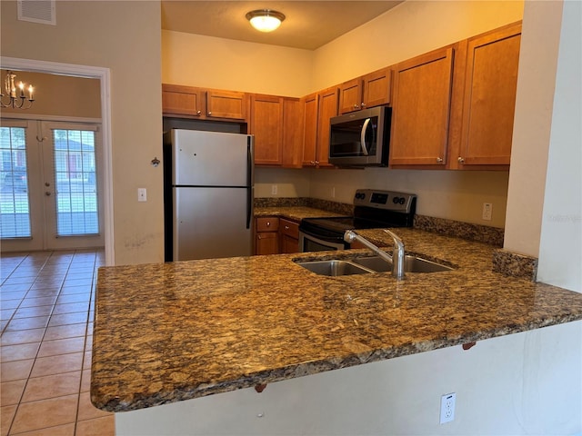 kitchen featuring appliances with stainless steel finishes, dark stone countertops, kitchen peninsula, and sink