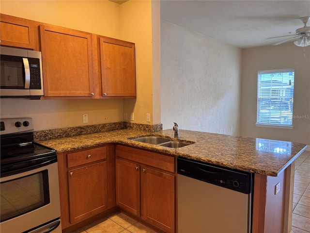 kitchen featuring stainless steel appliances, ceiling fan, light tile patterned flooring, dark stone counters, and kitchen peninsula