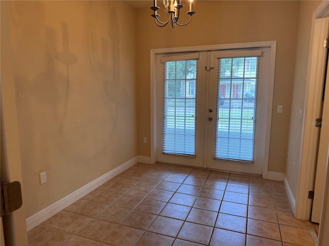 entryway with light tile patterned floors, french doors, and an inviting chandelier