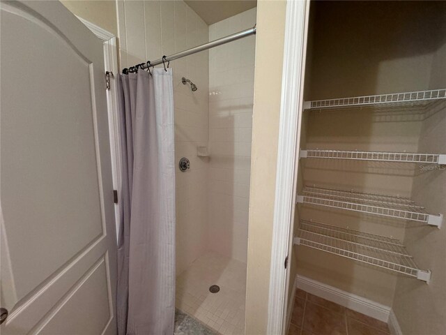 bathroom with a shower with shower curtain and tile patterned flooring