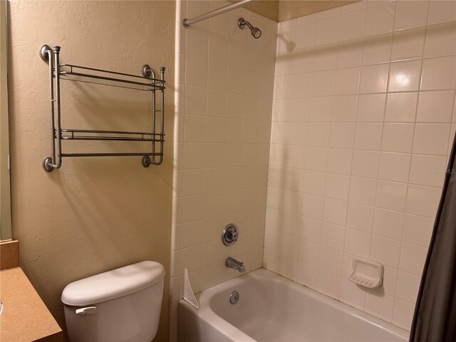 full bathroom with vanity, tiled shower / bath combo, and toilet