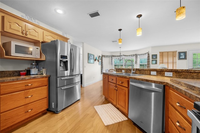 kitchen with appliances with stainless steel finishes, light hardwood / wood-style flooring, sink, and hanging light fixtures