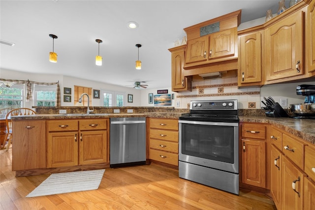 kitchen with light wood-type flooring, stainless steel appliances, decorative light fixtures, kitchen peninsula, and ceiling fan