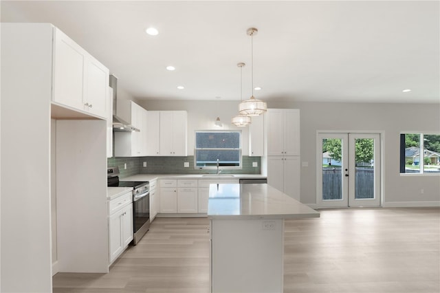 kitchen with light hardwood / wood-style floors, tasteful backsplash, a center island, white cabinets, and electric stove