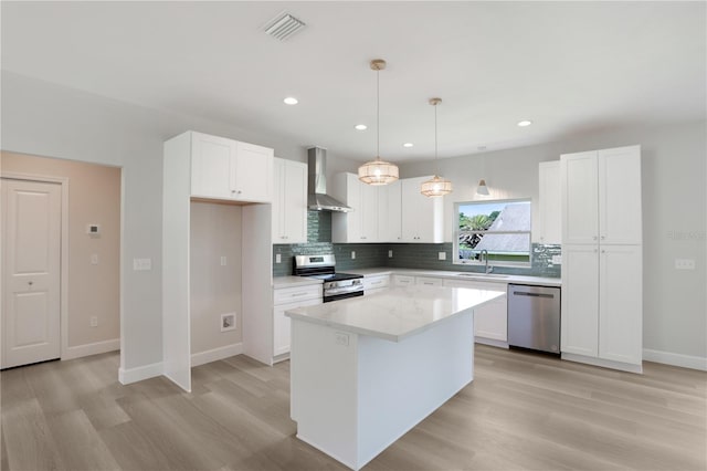 kitchen with appliances with stainless steel finishes, white cabinetry, and wall chimney exhaust hood