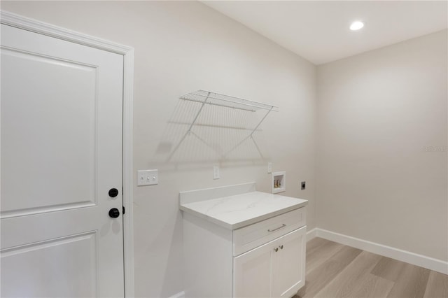 laundry room featuring electric dryer hookup, cabinets, light hardwood / wood-style flooring, and hookup for a washing machine