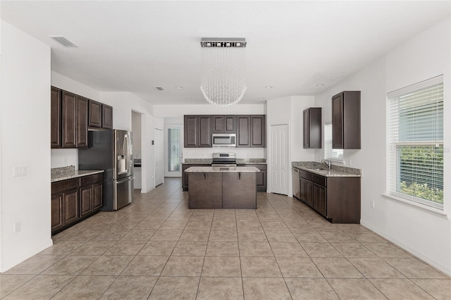 kitchen featuring a center island, stainless steel appliances, an inviting chandelier, and light tile flooring