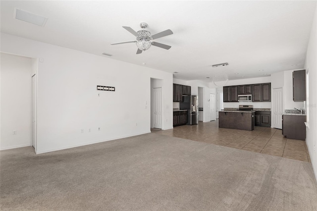 unfurnished living room featuring light carpet, sink, and ceiling fan