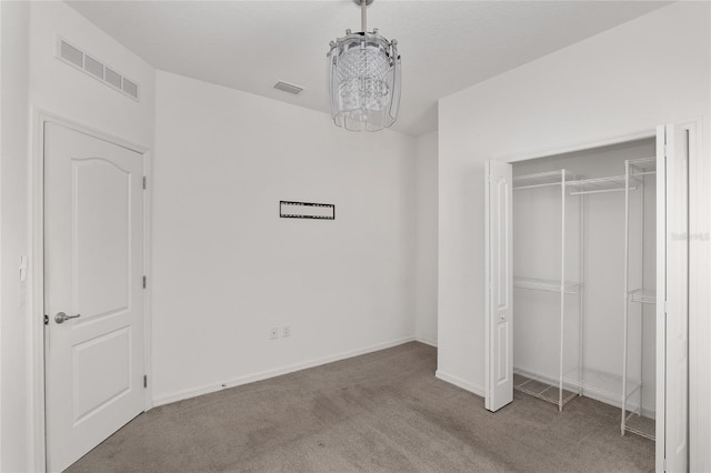 unfurnished bedroom with carpet, a closet, and a chandelier