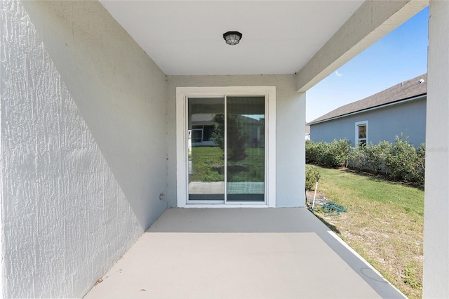 entrance to property featuring a patio area and a lawn