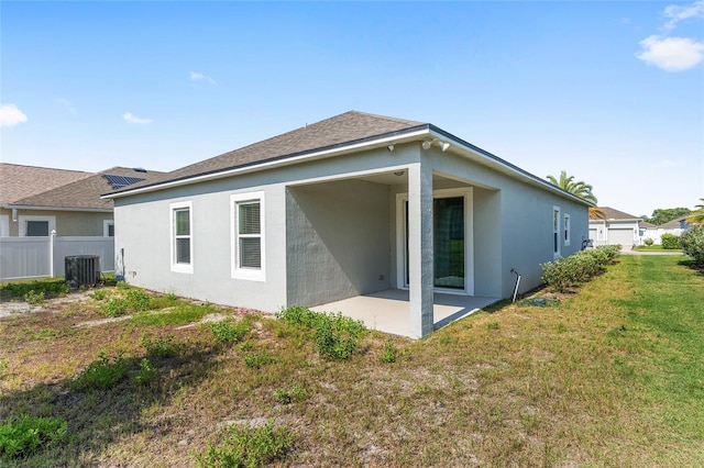 back of property with central AC, a lawn, and a patio area