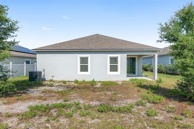 rear view of property featuring central AC unit and solar panels