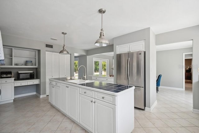 kitchen featuring a kitchen island with sink, white cabinets, sink, stainless steel fridge, and built in features