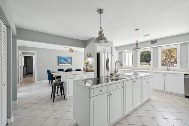 kitchen with white cabinets, sink, a kitchen island, and appliances with stainless steel finishes