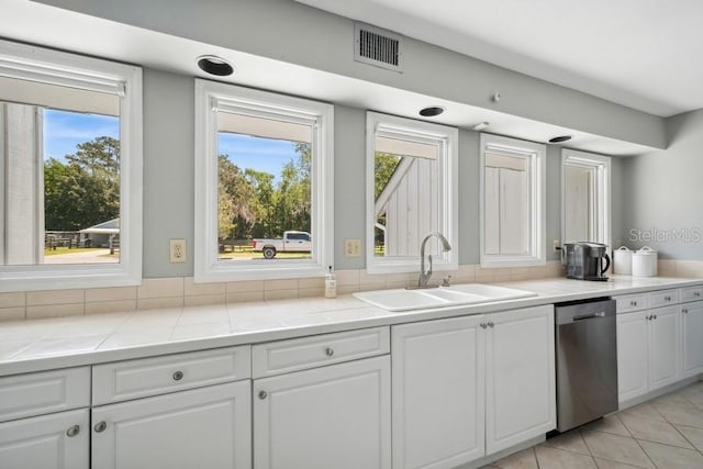 kitchen with white cabinetry, dishwasher, sink, tile countertops, and light tile patterned flooring