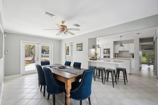 tiled dining area with french doors, ceiling fan, and crown molding