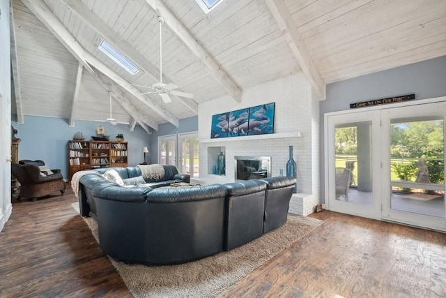 living room featuring a skylight, ceiling fan, beam ceiling, wood-type flooring, and a fireplace