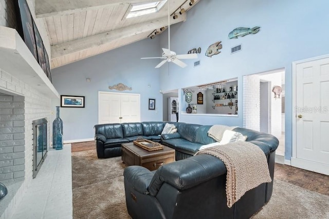 living room featuring beam ceiling, ceiling fan, a fireplace, and high vaulted ceiling