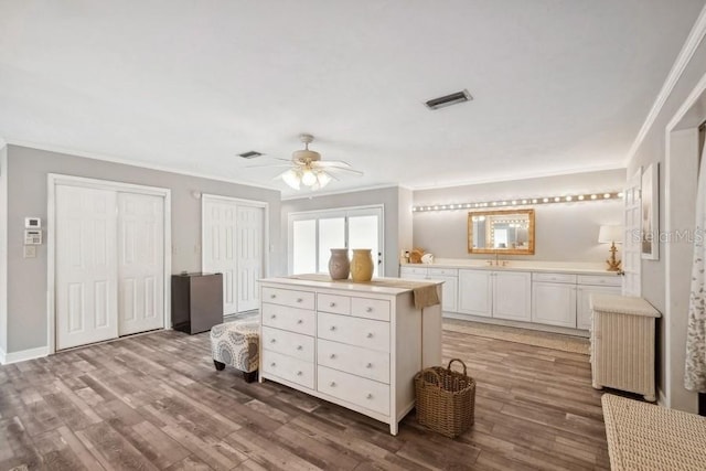 interior space with hardwood / wood-style floors, ornamental molding, and multiple closets