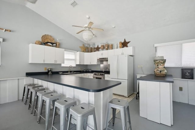 kitchen with white cabinets, white fridge, a kitchen bar, and vaulted ceiling